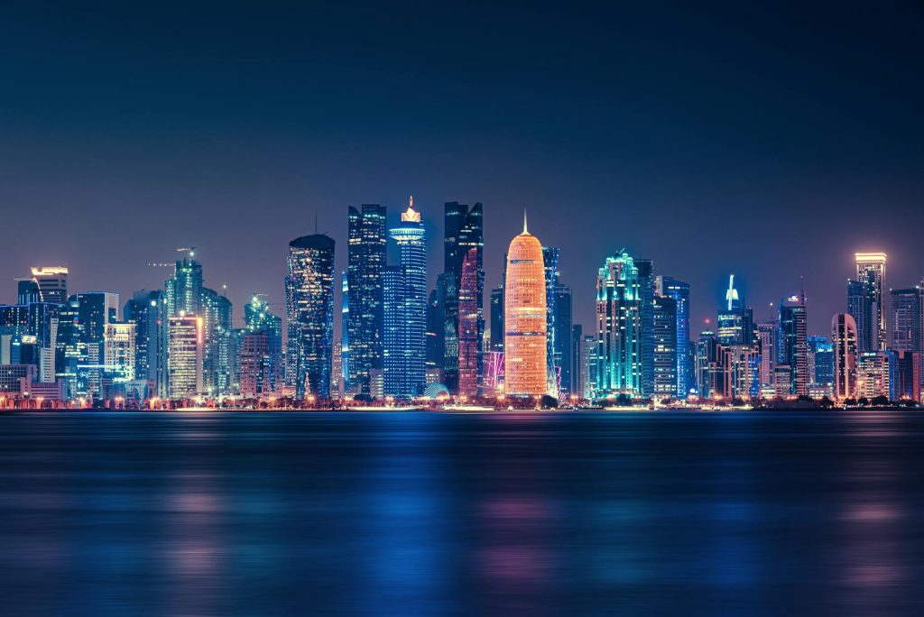 Body of water across Doha city buildings during nighttime.