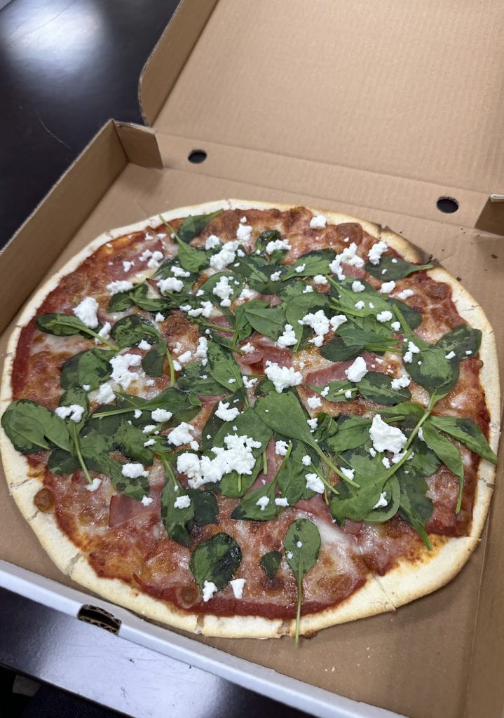 Gluten-free pizza with green leaves and cheese from Amora Pizza in Doha, Qatar.