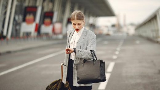 worried young businesswoman with suitcase hurrying on flight on urban background