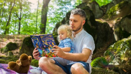 photo of man and child reading book during daytime