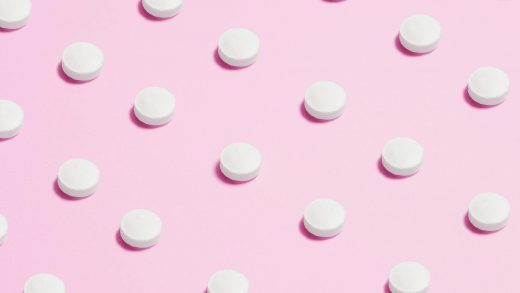 white round capsule on pink background close up photography